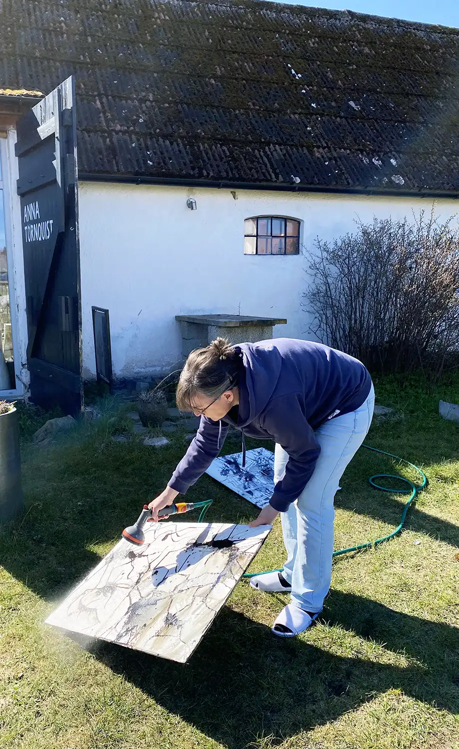 Helene Engström spolar en akvarelltavla med trädgårdsslangen. Kursen är Tid för fördjupning hos Anna Törnquist.